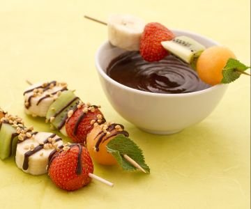 Fruit skewers with chocolate sauce and hazelnut crumble