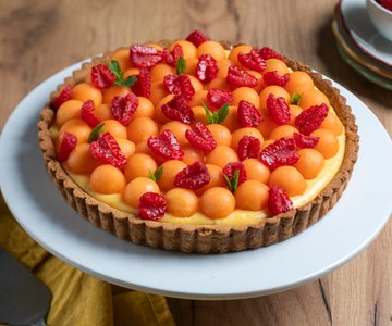 Tart with cream, melon, and raspberries