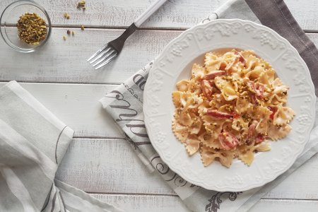 Farfalle with Parmesan cream, speck and pistachios