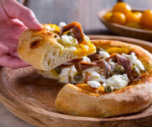 Pizza with yellow cherry tomatoes, anchovies, and capers