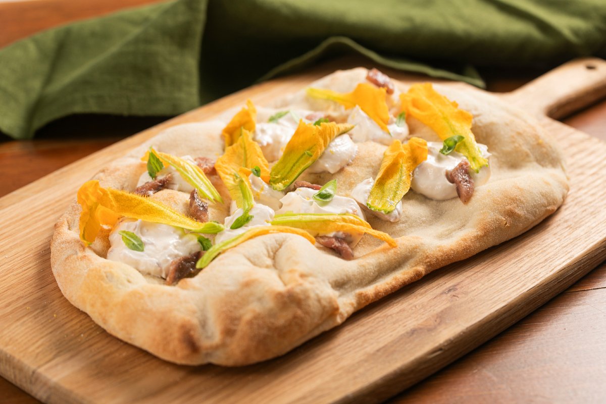 Pinsa with zucchini flowers, anchovies and cheese cream